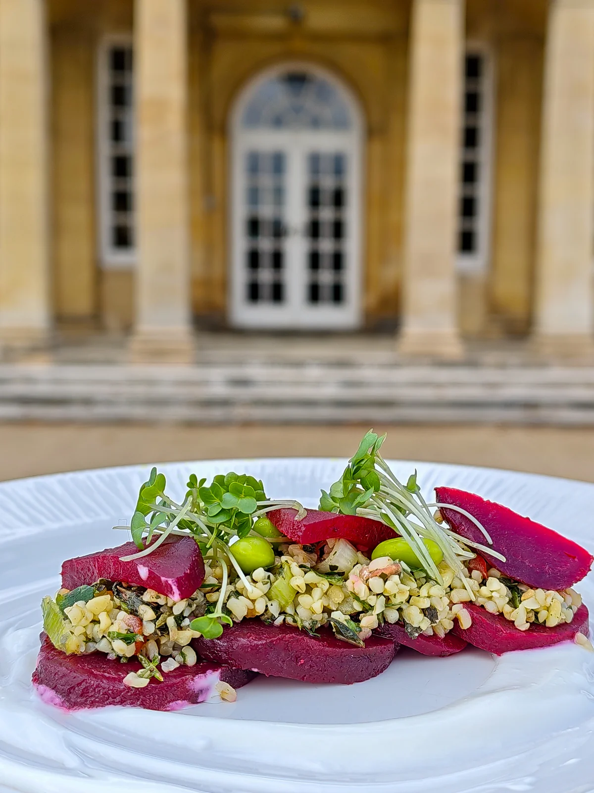 Sliced beetroot and a herbed grain salad, the manor portico behind